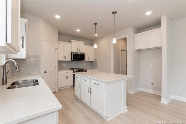 kitchen featuring a sink, stainless steel appliances, backsplash, baseboards, and white cabinets