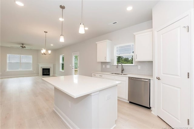 kitchen featuring decorative backsplash, white cabinets, a sink, a center island, and dishwasher