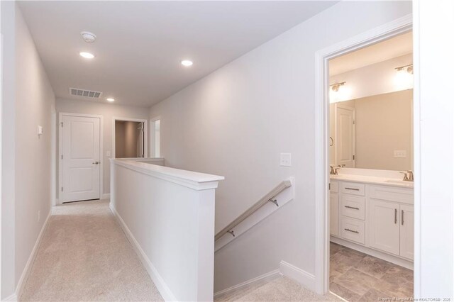 hall featuring recessed lighting, a sink, an upstairs landing, visible vents, and baseboards