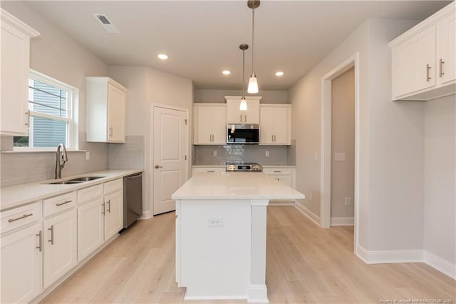 kitchen with white cabinetry, a sink, appliances with stainless steel finishes, and light wood-style floors