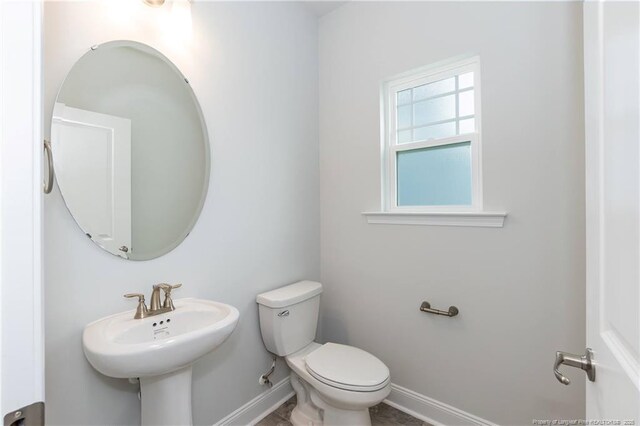 bathroom with a sink, toilet, and baseboards