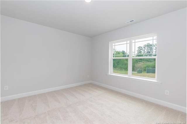 empty room featuring visible vents, light carpet, and baseboards