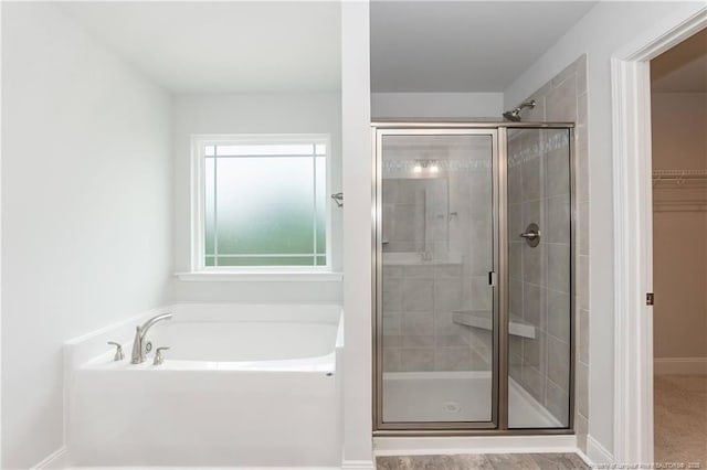 full bathroom with a walk in closet, baseboards, a stall shower, and a garden tub