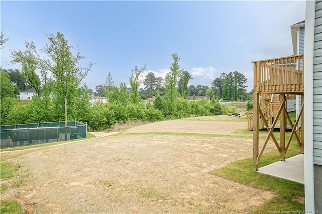 view of yard featuring a deck, fence, and stairs