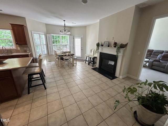 living room featuring light tile patterned floors, a chandelier, a fireplace with flush hearth, and baseboards
