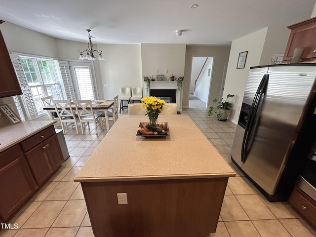 kitchen featuring stainless steel fridge, light countertops, a chandelier, a kitchen island, and light tile patterned floors