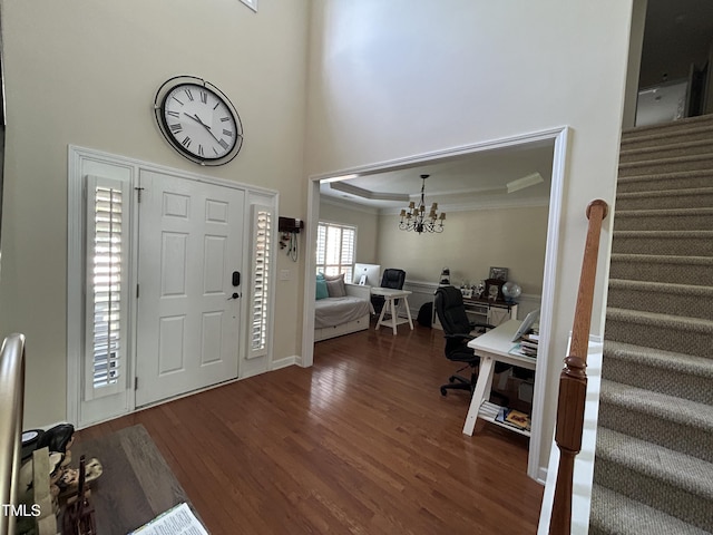 entrance foyer featuring stairs, ornamental molding, wood finished floors, a chandelier, and a towering ceiling