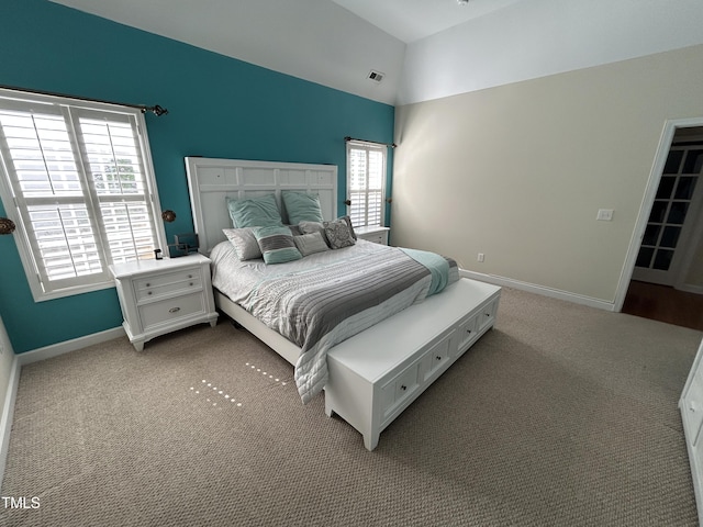 bedroom with vaulted ceiling, light colored carpet, and baseboards