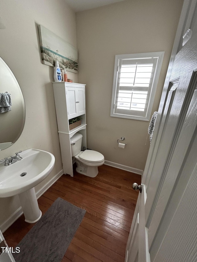 bathroom with toilet, hardwood / wood-style floors, and baseboards