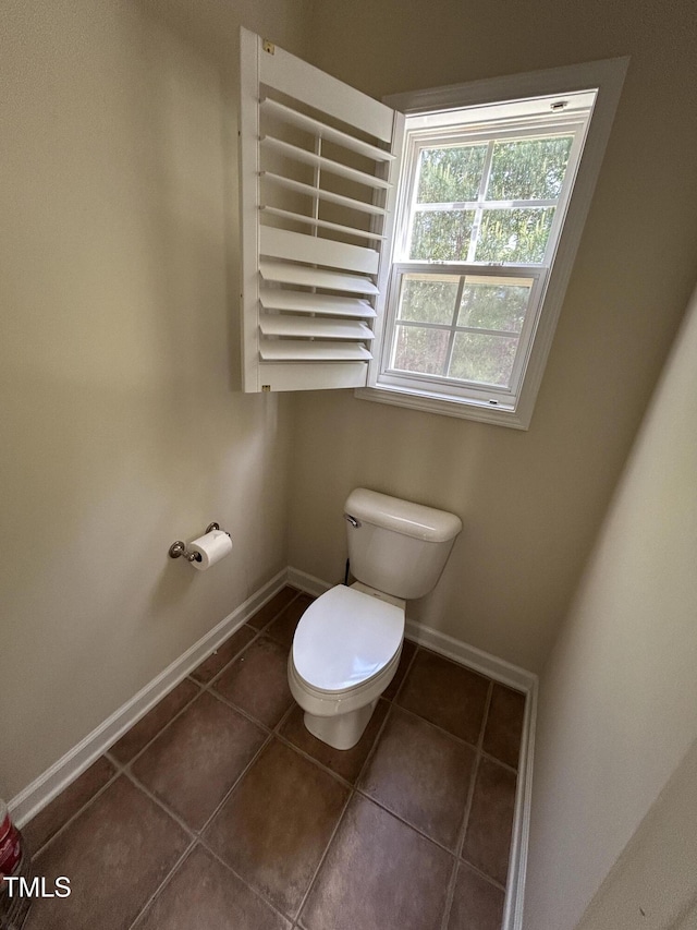 bathroom with toilet, baseboards, and tile patterned floors