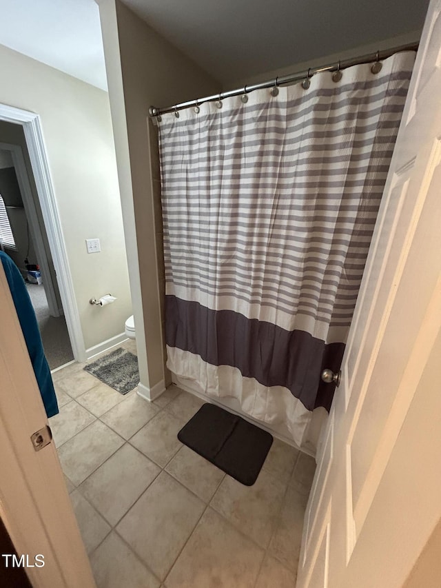 full bathroom featuring tile patterned floors, toilet, a shower with curtain, and baseboards