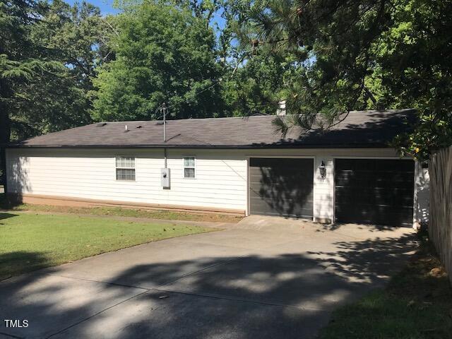 5002 Wickham Rd, Raleigh, NC 27606 - view of side of property with driveway, a garage, and a yard