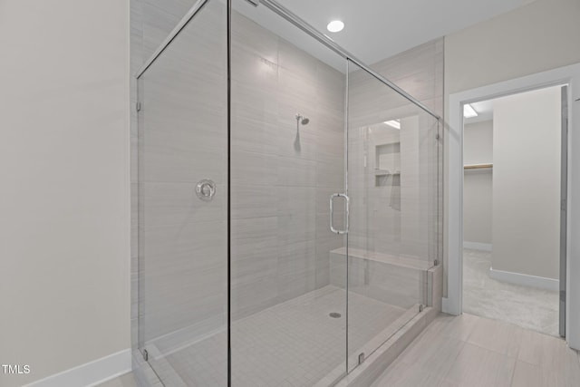 bathroom featuring a shower stall, baseboards, and a spacious closet