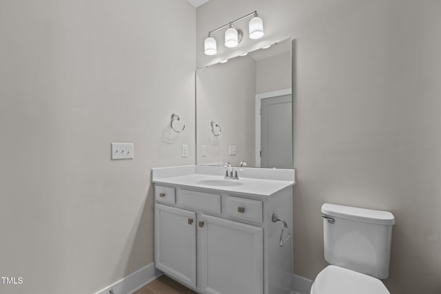 half bathroom with toilet, vanity, and baseboards