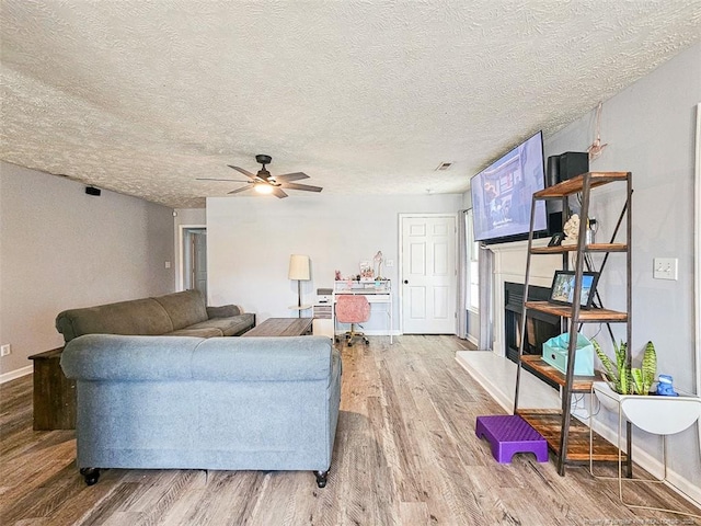 6314 Greycliff Dr, Fayetteville, NC 28314 - living area featuring wood finished floors, a fireplace with raised hearth, ceiling fan, baseboards, and a textured ceiling