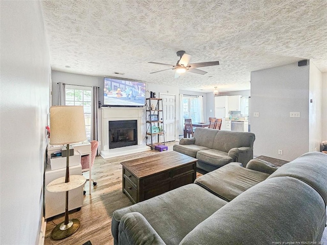 6314 Greycliff Dr, Fayetteville, NC 28314 - living room with wood finished floors, ceiling fan, a fireplace with raised hearth, and a textured ceiling