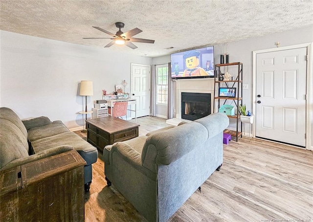 6314 Greycliff Dr, Fayetteville, NC 28314 - living area featuring light wood-style flooring, a ceiling fan, a textured ceiling, a fireplace with raised hearth, and baseboards