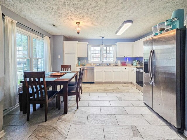 6314 Greycliff Dr, Fayetteville, NC 28314 - kitchen featuring stainless steel appliances, white cabinets, light countertops, hanging light fixtures, and a sink