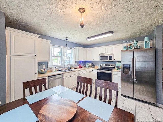 6314 Greycliff Dr, Fayetteville, NC 28314 - kitchen featuring appliances with stainless steel finishes, a sink, white cabinetry, light countertops, and a textured ceiling