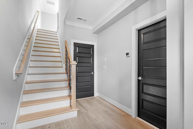 stairway featuring wood finished floors, crown molding, and baseboards