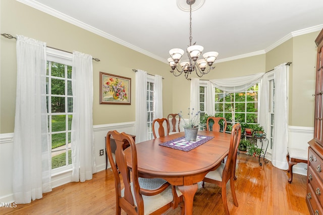 dining space with a chandelier, ornamental molding, light wood-style floors, wainscoting, and plenty of natural light