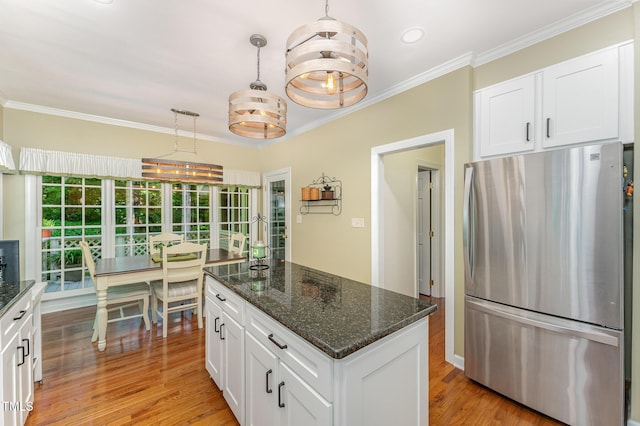 kitchen featuring freestanding refrigerator, white cabinets, crown molding, dark stone countertops, and light wood-type flooring