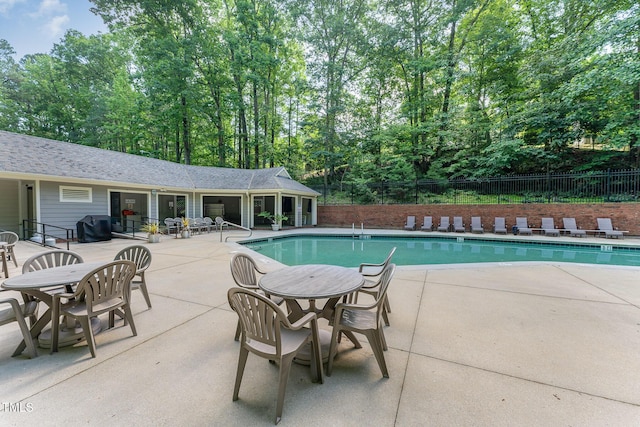 community pool featuring fence, a patio area, and grilling area