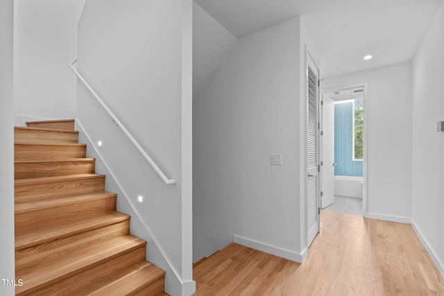 stairway featuring recessed lighting, wood finished floors, and baseboards