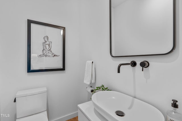 bathroom with toilet, wood finished floors, a sink, and baseboards