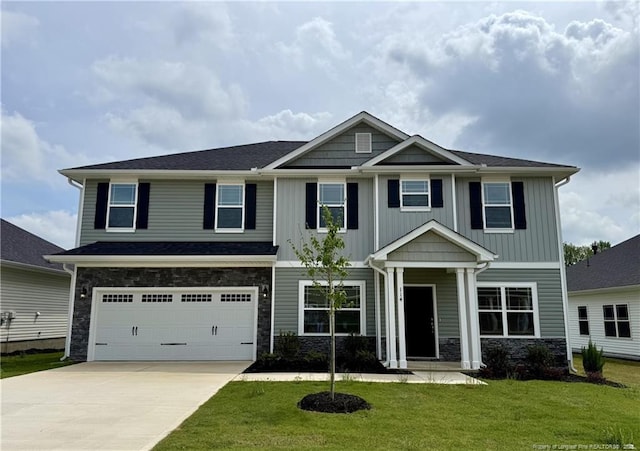 craftsman-style house with a garage, concrete driveway, a front lawn, and stone siding