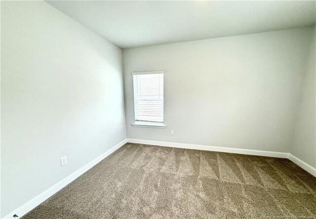 unfurnished room with dark carpet and baseboards