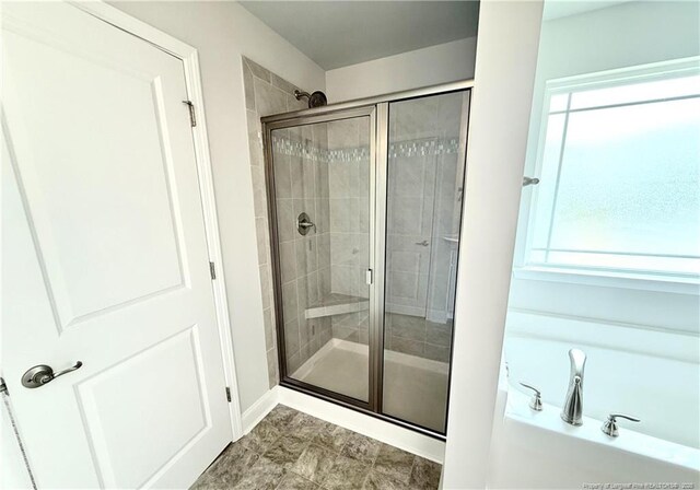 full bathroom featuring a garden tub, a stall shower, and baseboards