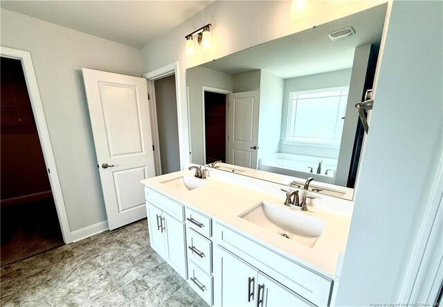 bathroom with visible vents, a garden tub, double vanity, and a sink