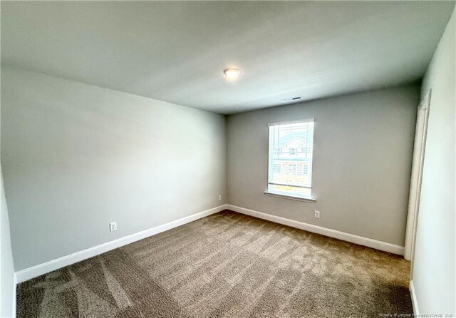 carpeted spare room featuring baseboards and visible vents