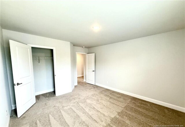 unfurnished bedroom with a closet, light carpet, and baseboards