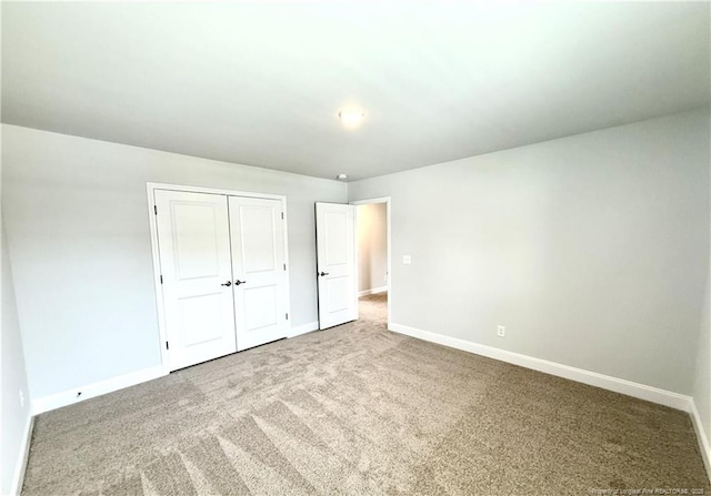 unfurnished bedroom featuring baseboards, carpet floors, and a closet