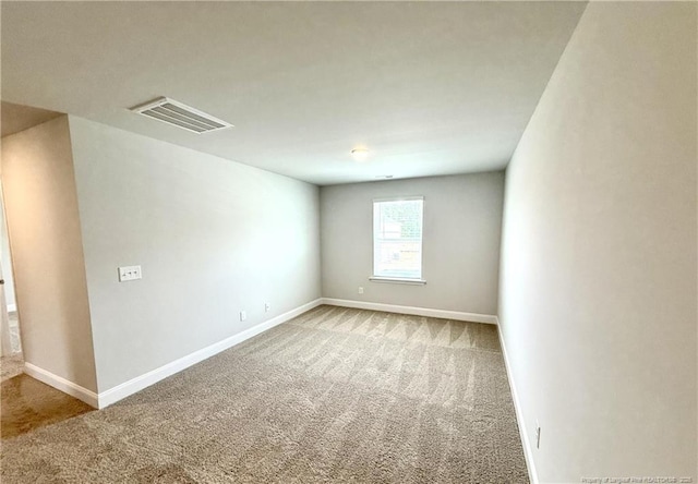 carpeted spare room featuring visible vents and baseboards
