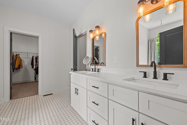 bathroom with double vanity, tile patterned floors, visible vents, and a sink