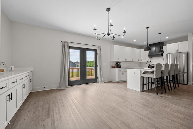 kitchen featuring french doors, tasteful backsplash, freestanding refrigerator, custom exhaust hood, and an inviting chandelier
