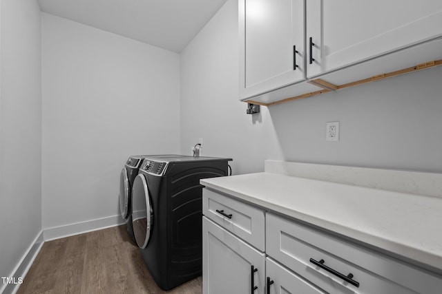 laundry area featuring baseboards, dark wood-type flooring, cabinet space, and washer and dryer