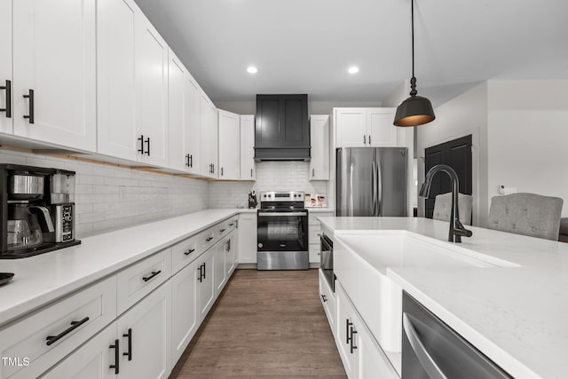 kitchen featuring custom exhaust hood, light countertops, white cabinetry, appliances with stainless steel finishes, and backsplash