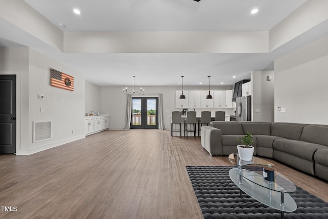 living room featuring recessed lighting, visible vents, a chandelier, and light wood-type flooring