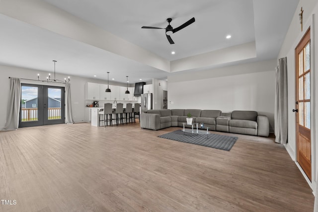 living room with recessed lighting, french doors, light wood finished floors, and ceiling fan with notable chandelier