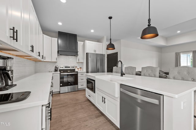 kitchen with decorative backsplash, appliances with stainless steel finishes, a sink, light countertops, and under cabinet range hood