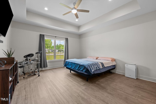 bedroom featuring baseboards, recessed lighting, wood finished floors, and a raised ceiling