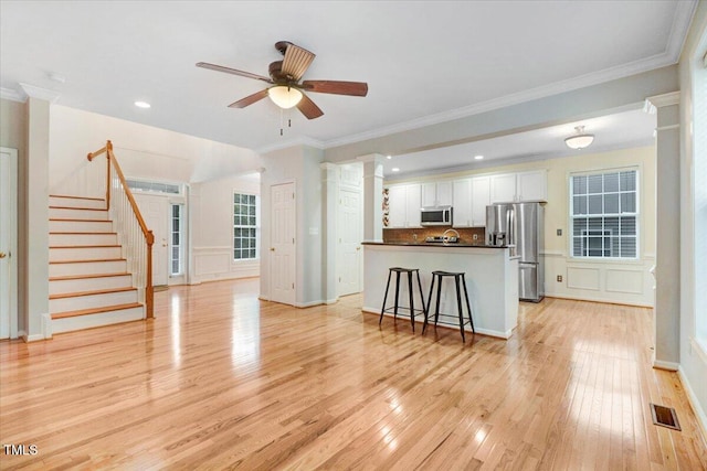 1480 Big Leaf Loop, Apex, NC 27502 - kitchen with appliances with stainless steel finishes, dark countertops, white cabinets, light wood-style floors, and decorative columns