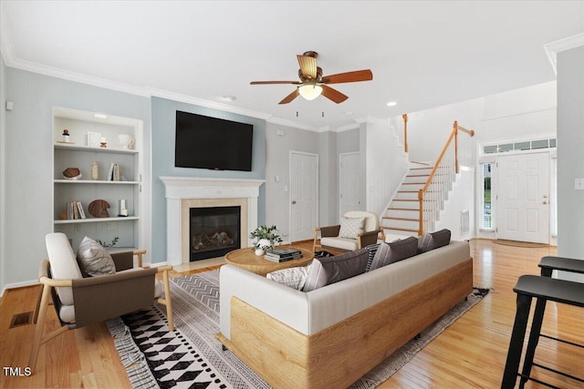 1480 Big Leaf Loop, Apex, NC 27502 - living area featuring stairs, a ceiling fan, built in shelves, wood finished floors, and a fireplace with flush hearth