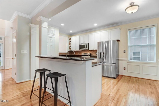 1480 Big Leaf Loop, Apex, NC 27502 - kitchen with stainless steel appliances, light wood finished floors, a breakfast bar, dark countertops, and ornamental molding