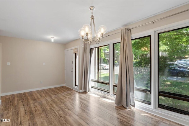 unfurnished room with baseboards, a chandelier, and wood finished floors