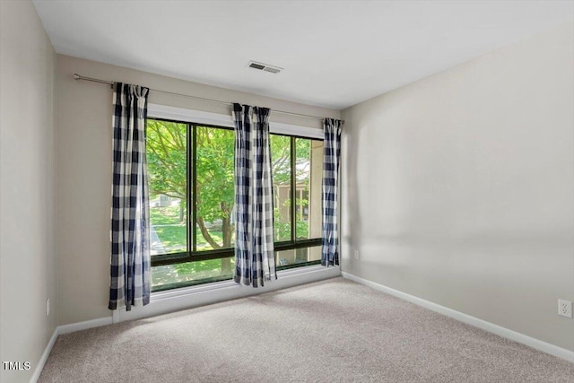 carpeted empty room featuring baseboards and visible vents